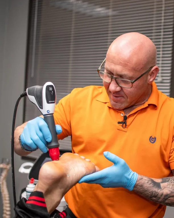 Dr. Tim Ballitch applying shockwave therapy to the bottom of a patient's foot at Muscle Chiropractic